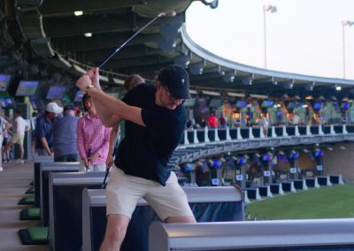 woman taking a swing at golf ball at TopGolf